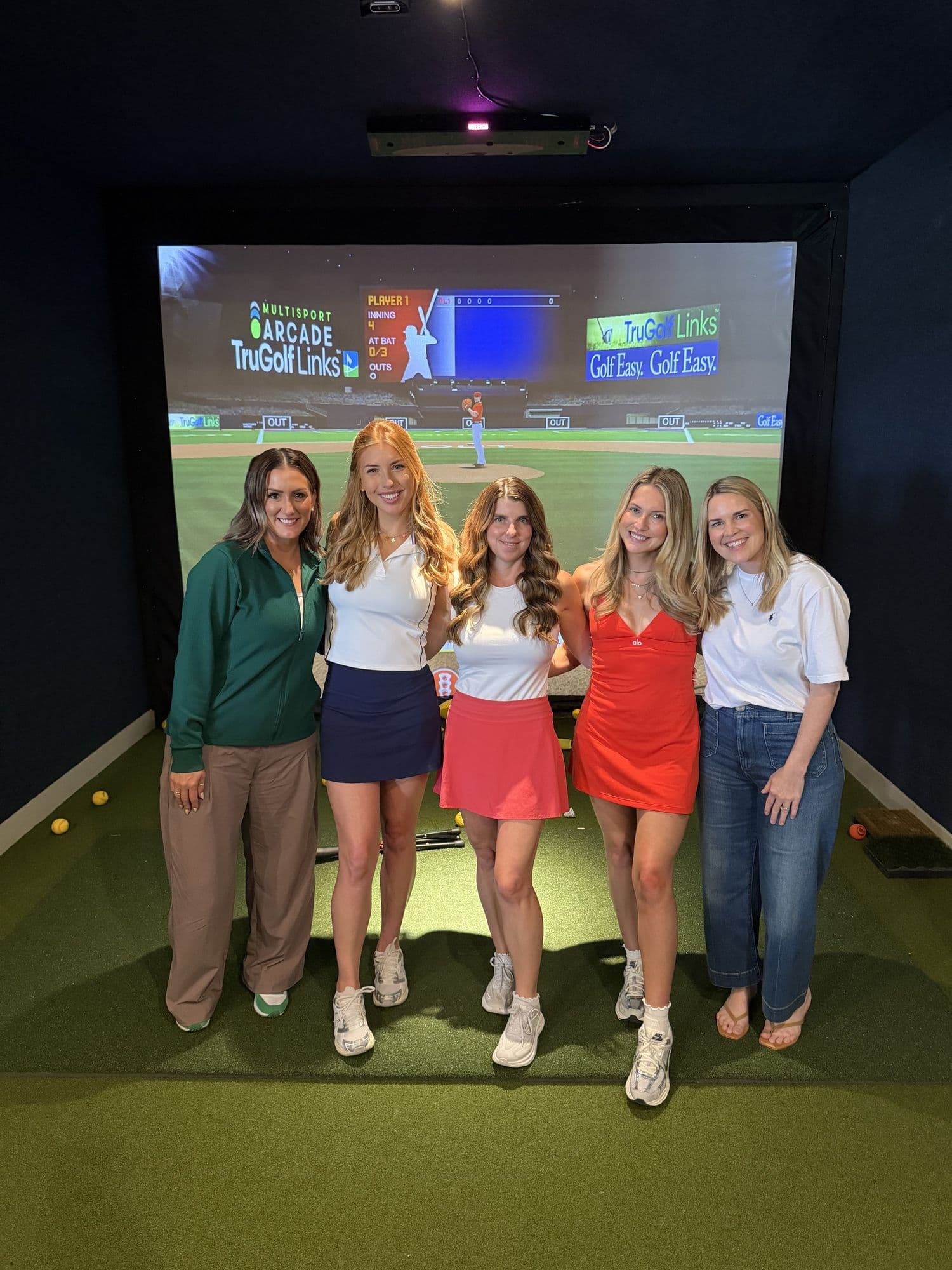 A group of friends celebrating in a simulator bay at The Golf House