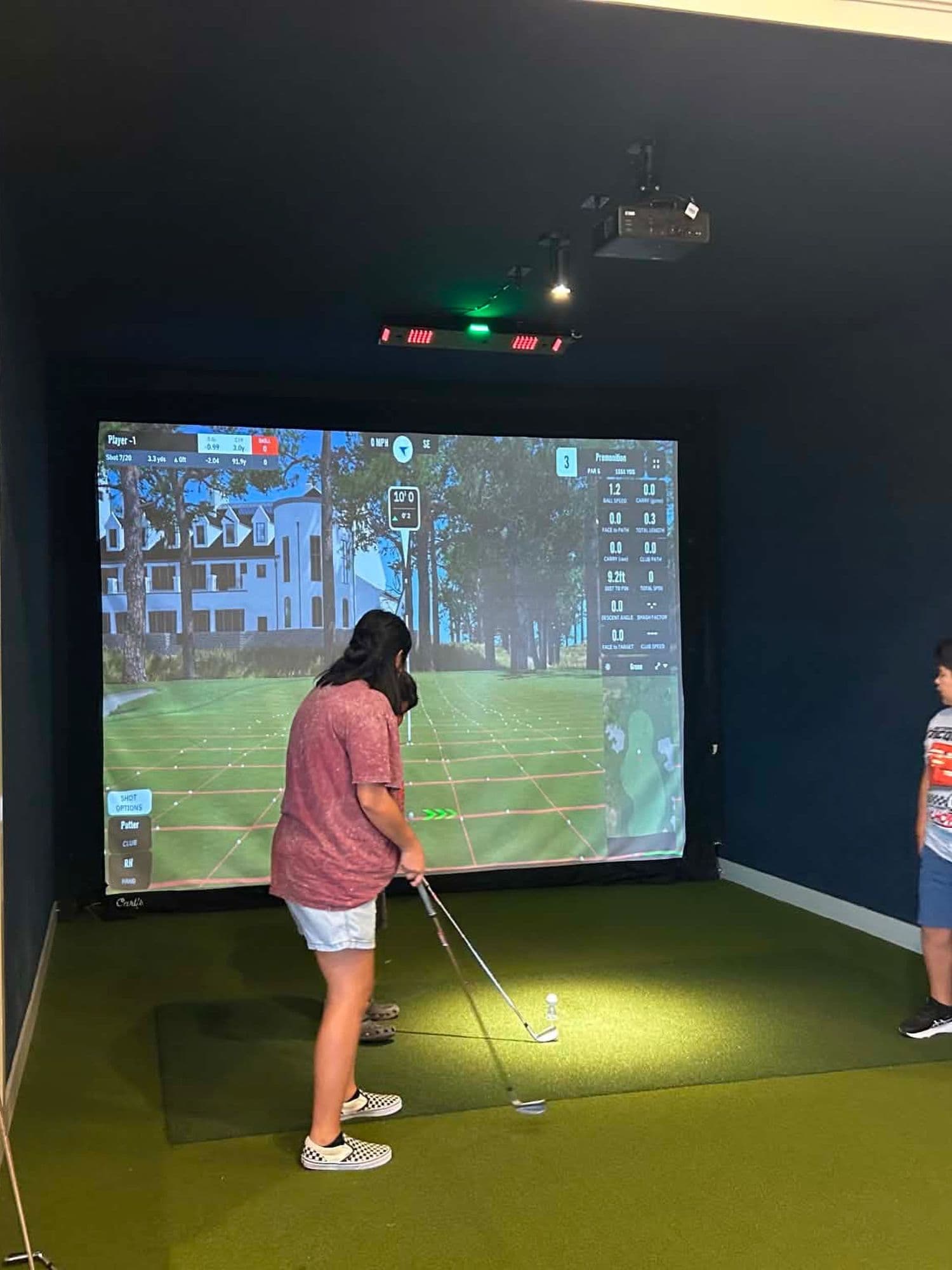 A junior golfer putting on a simulator bay