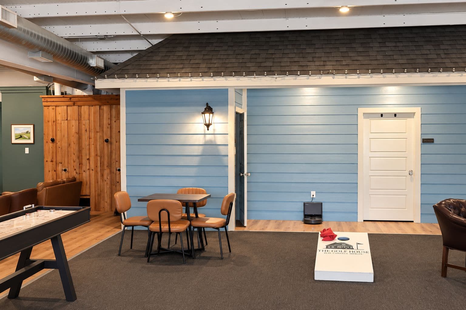 Cornhole boards and lounge tables in The Golf House games area