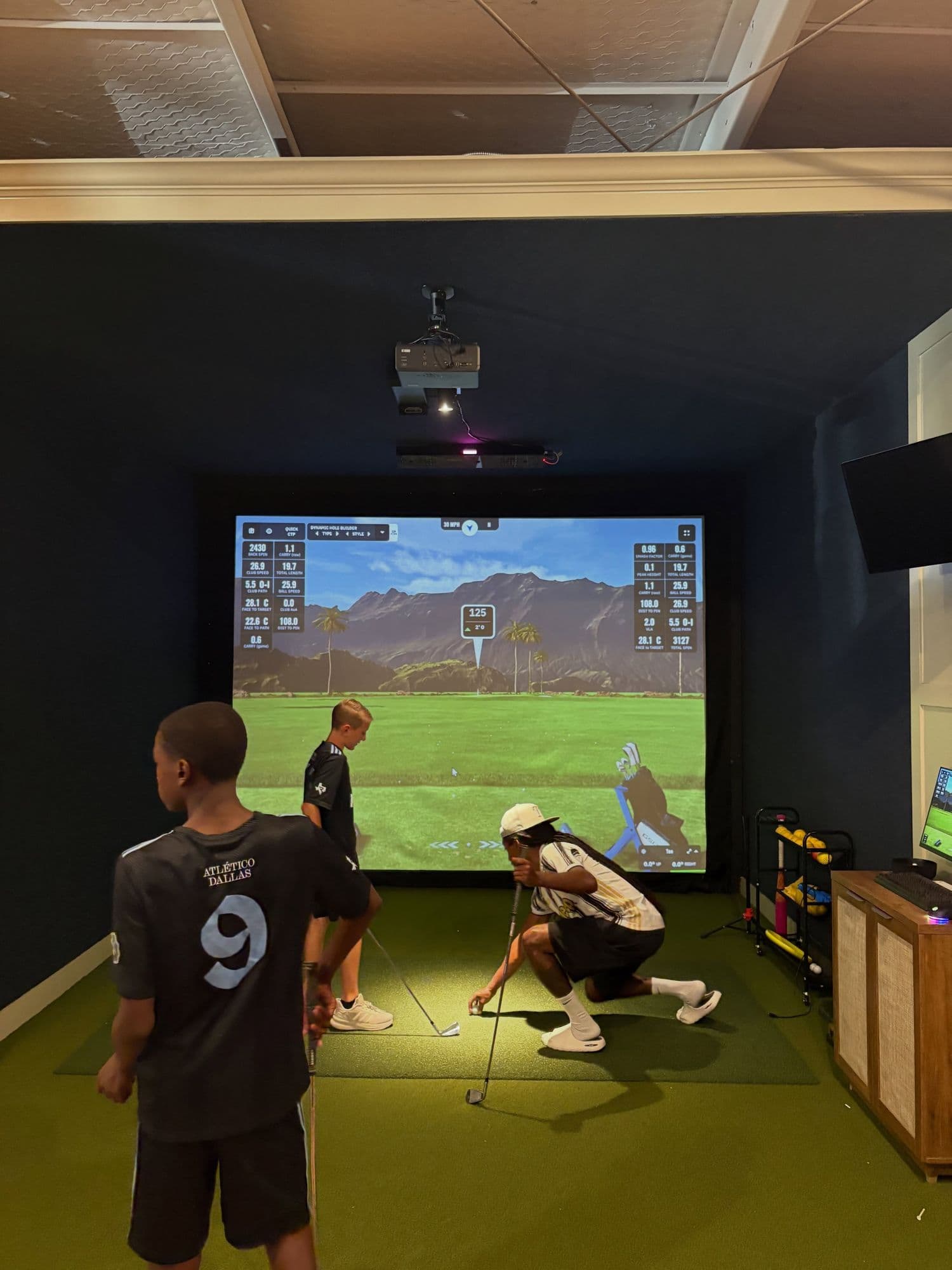 Kids taking turns on the simulator at a Golf House camp