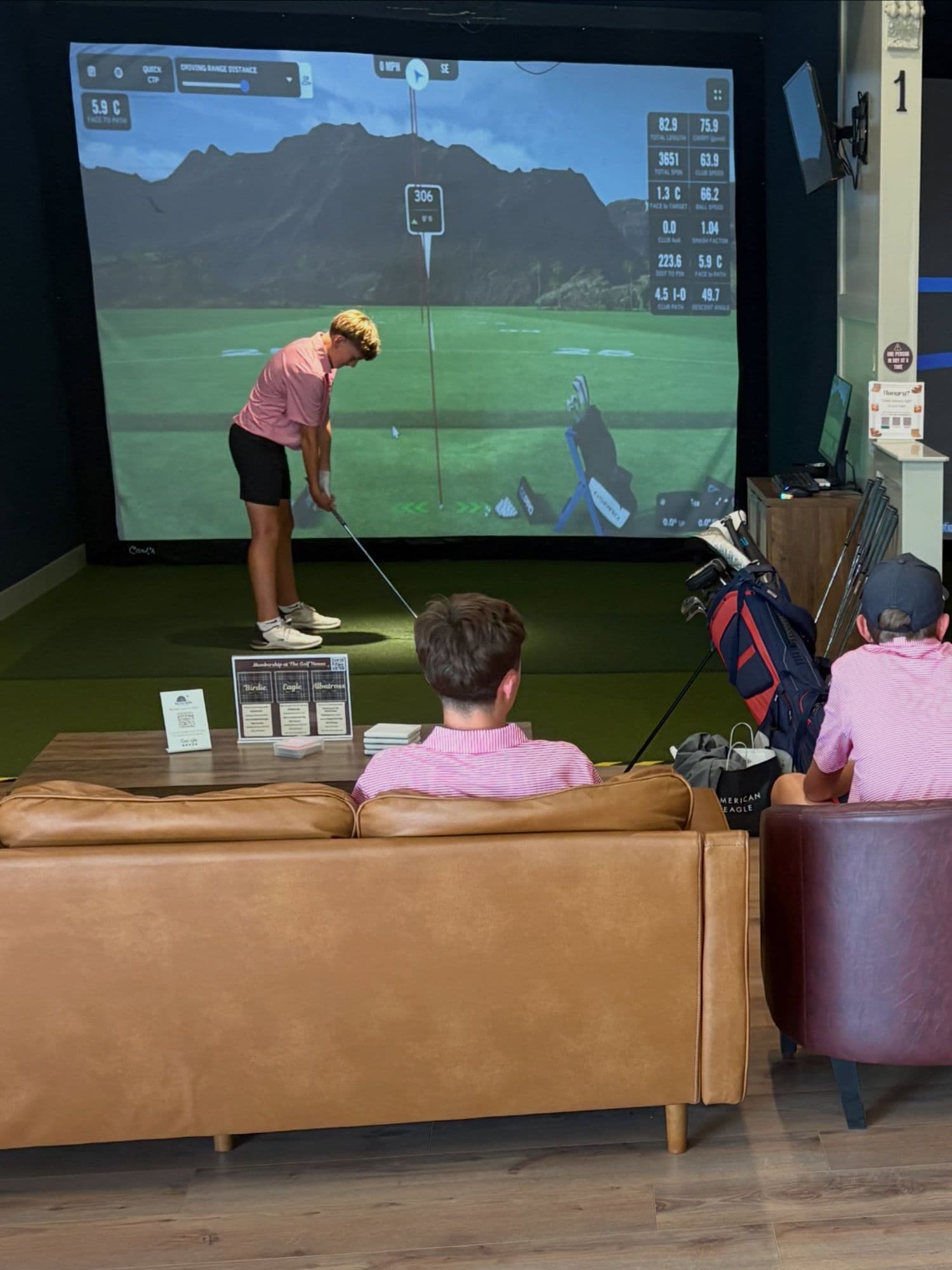 A junior golfer mid-swing on a simulator bay