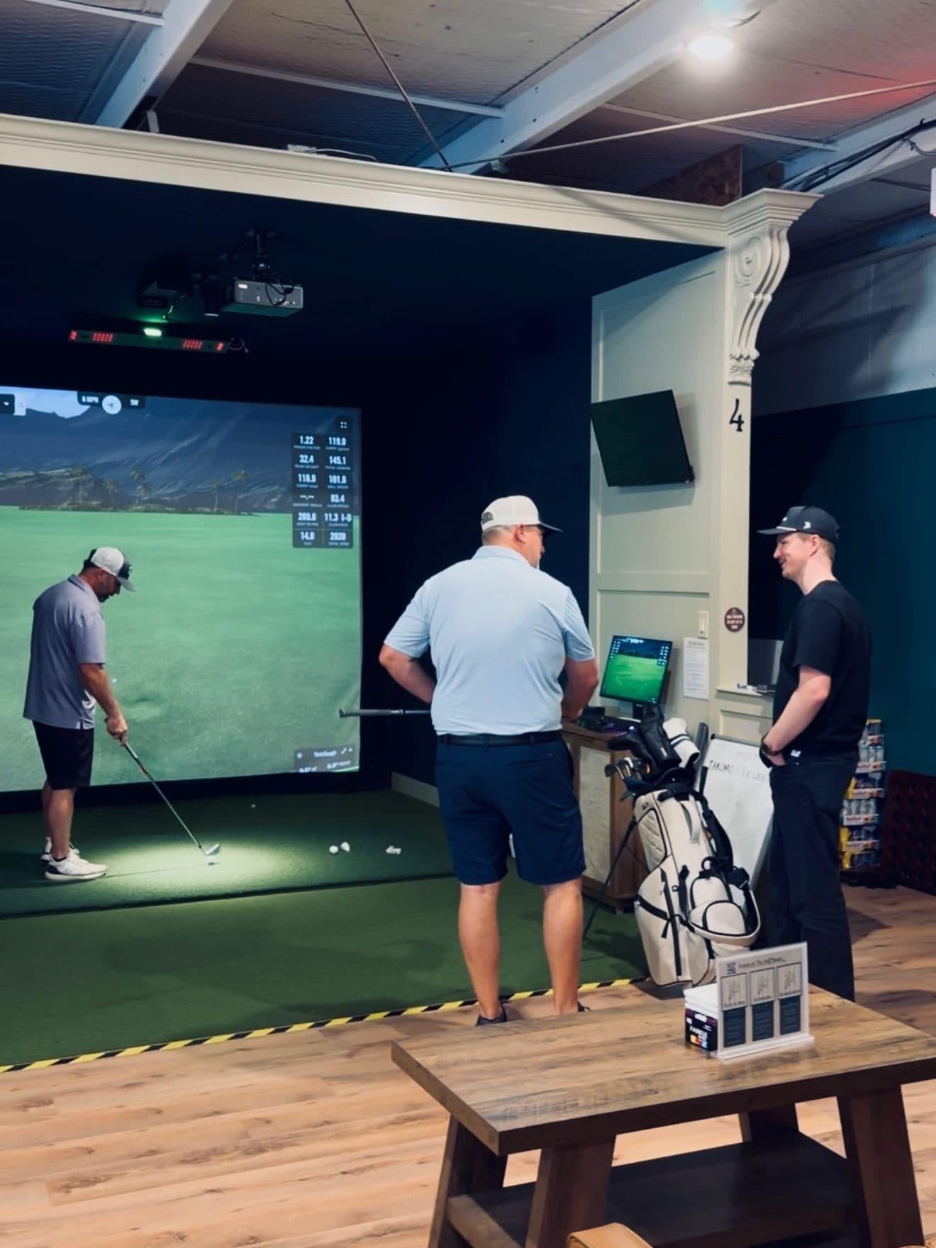 A golfer checking ball data on a simulator bay